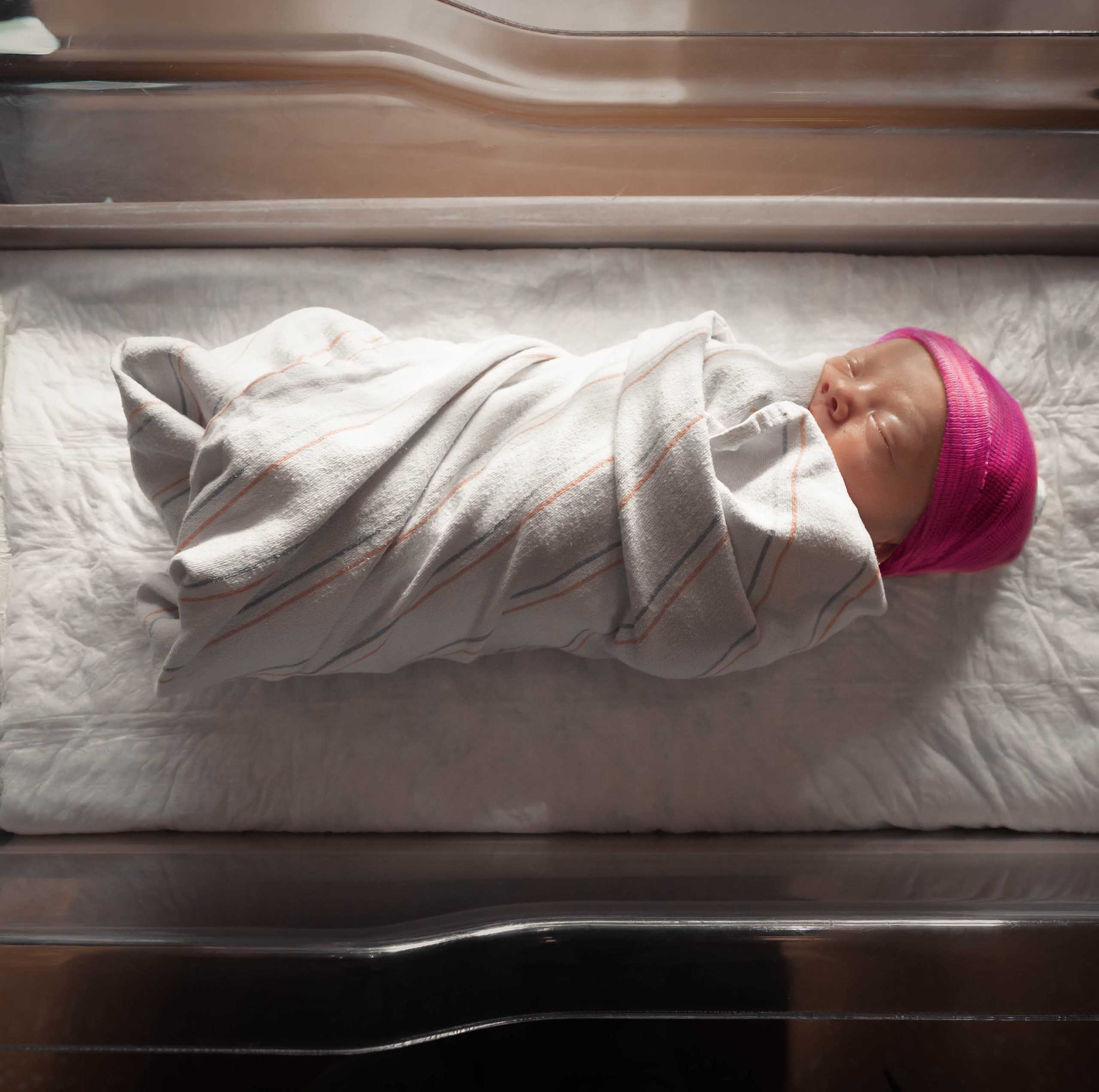 Wrapped premature baby with pink hat